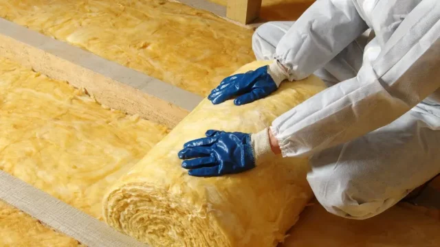 Installer fitting loft insulation rolls in a Manchester home